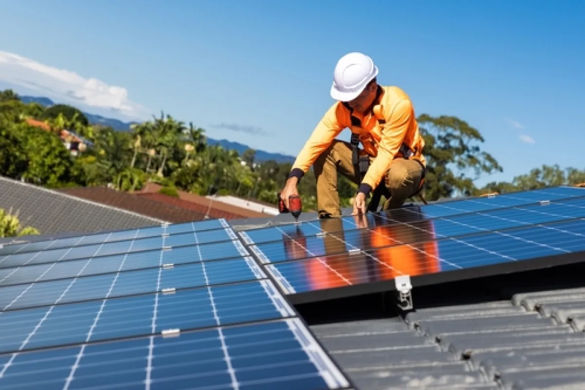 Man on roof adding solar PV panels.